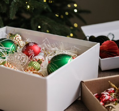 Red and green Christmas ornaments packed neatly into a white box.