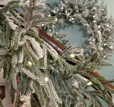 A wreath reflected in the mirror it's hung on.